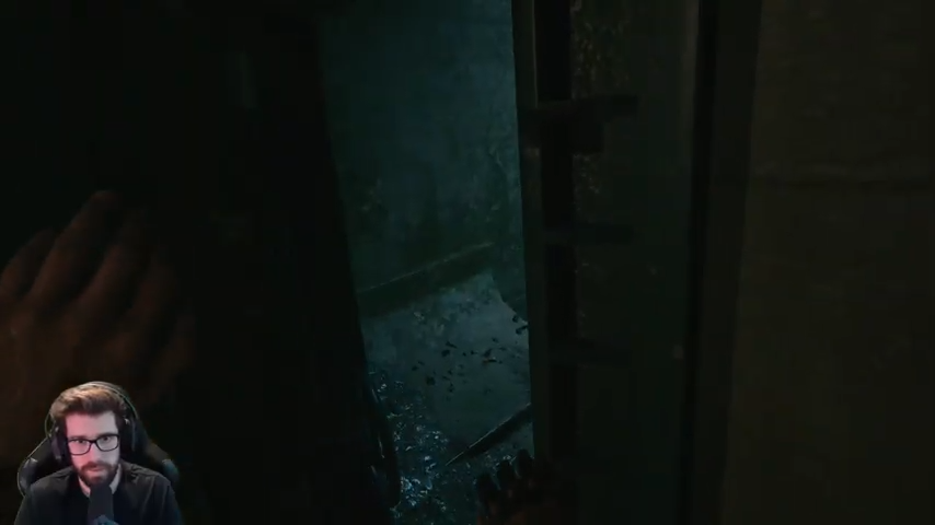 Aidan bracing against the wall while squeezing through a narrow opening toward the lower passage